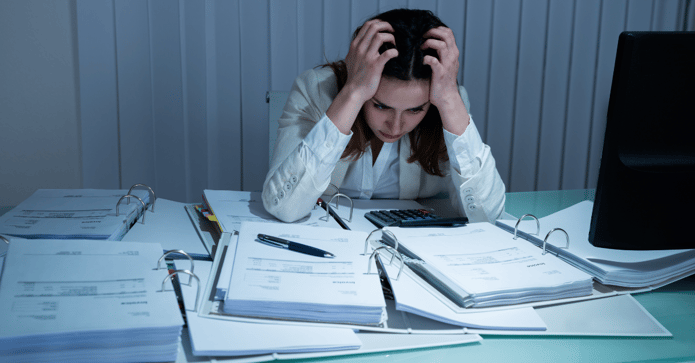 Frustrated woman at a desk full of paperwork