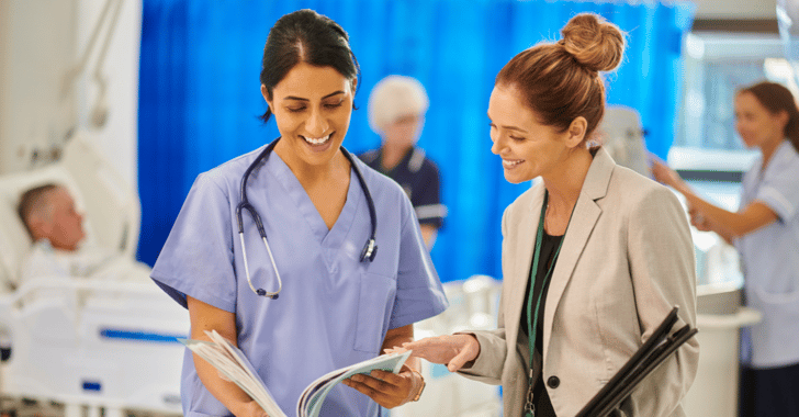 A female doctor smiles over some paperwork with a healthcare administrator